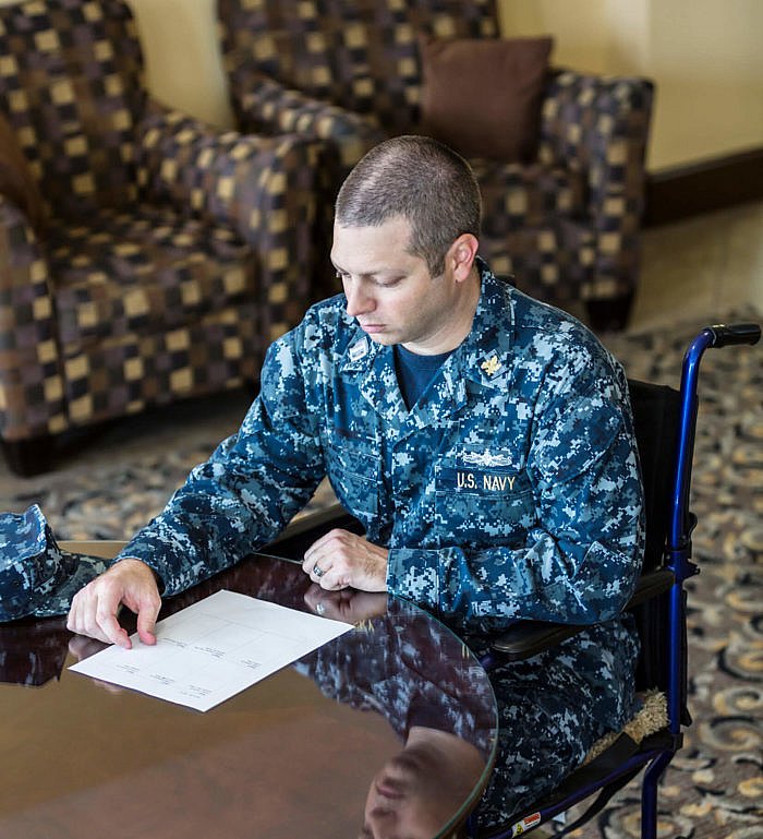 US Navy Officer Sitting In Wheelchair Reading Document.