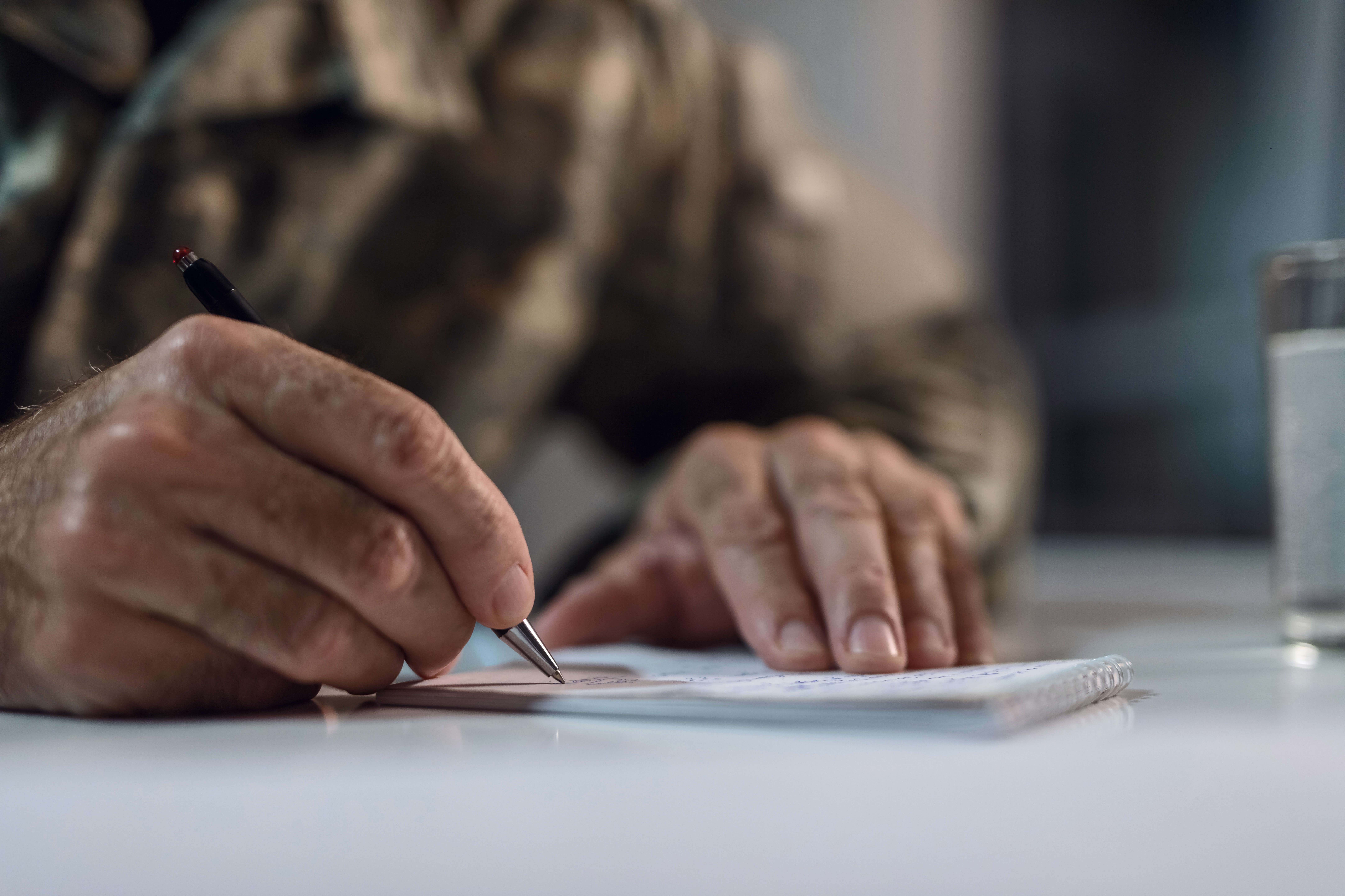 Veteran in military uniform filling out disability benefits paperwork for Blue Water Navy Agent Orange claim.