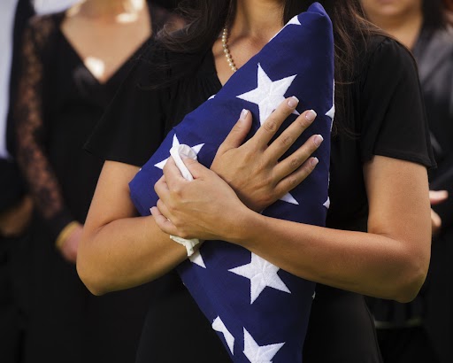 A woman holding a folded American flag at a funeral.