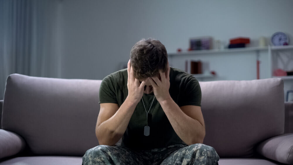 Nervous male military suffering depression, sitting alone at home, PTSD concept