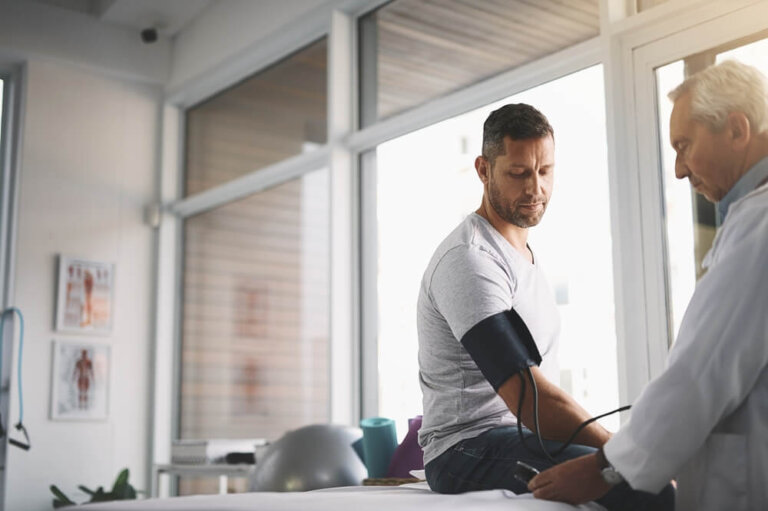 Healthcare, man and doctor in clinic for blood pressure, checkup and assessment in office.