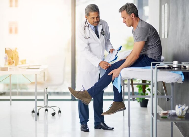 mature doctor examining his patient who is concerned about his knee