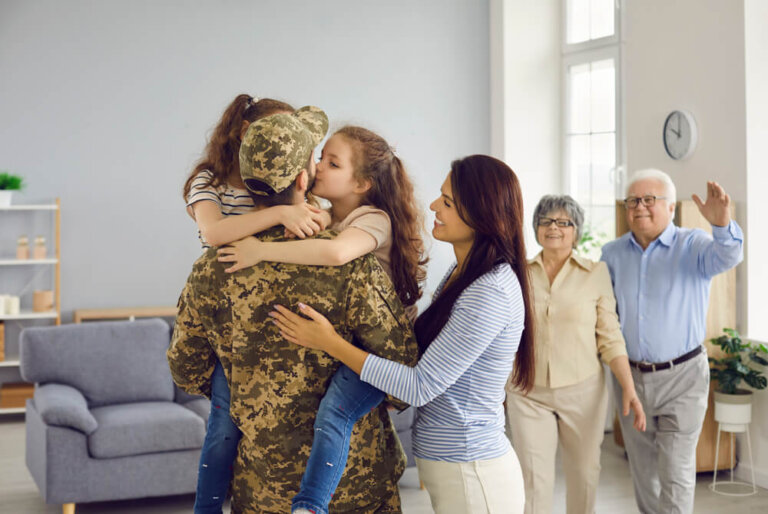 Emotional portrait of an unrecognizable man in military uniform embracing his large family.