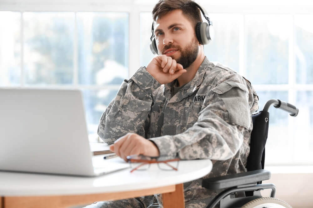 Veteran in wheelchair filing a VA disability claim online with help from a disability attorney