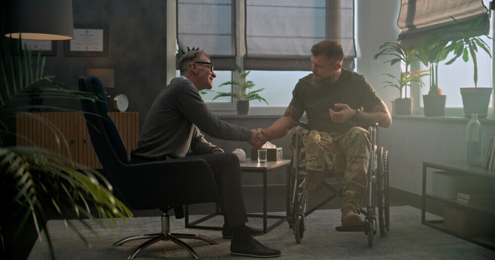VA disability appeals lawyer meeting with a disabled veteran in a wheelchair to discuss denied benefits claim.