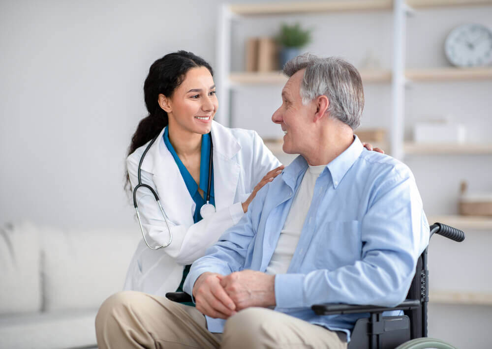 Doctor supporting elderly male patient in wheelchair for SSDI disability documentation.