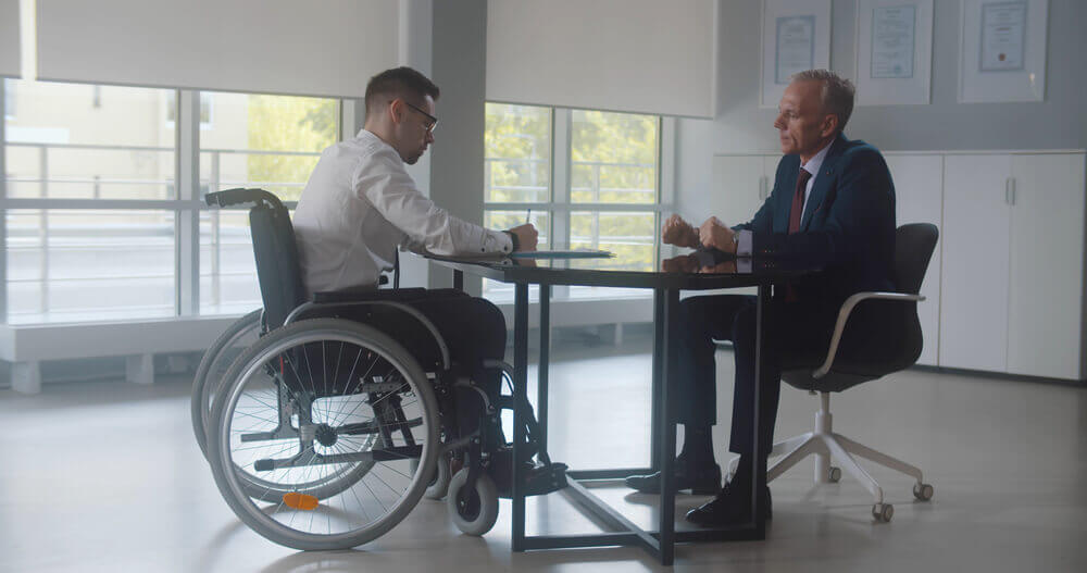 Disabled man in wheelchair meeting with disability lawyer to discuss SSDI or VA benefits claim