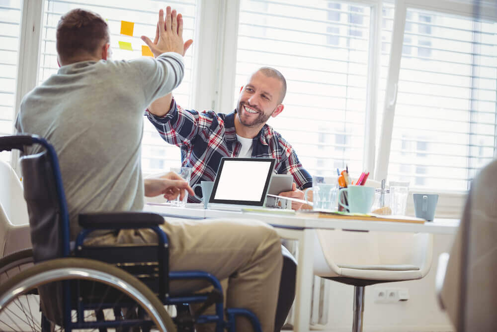 Handicap man giving high-five to colleague because he was approved for SSD benefits