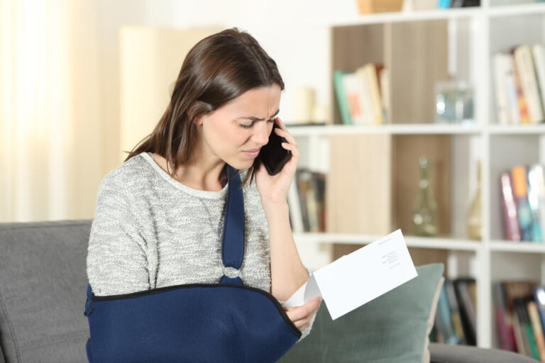 Injured woman reading a Social Security disability denial letter while calling for legal help