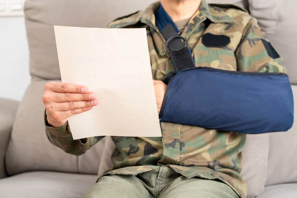 Injured veteran in uniform reading VA disability decision letter about retroactive back pay benefits.