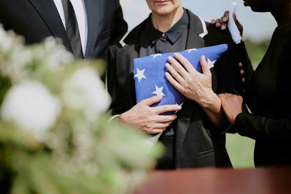 Widow holding a folded American flag at a military funeral, symbolizing VA survivor and dependent benefits for families of veterans