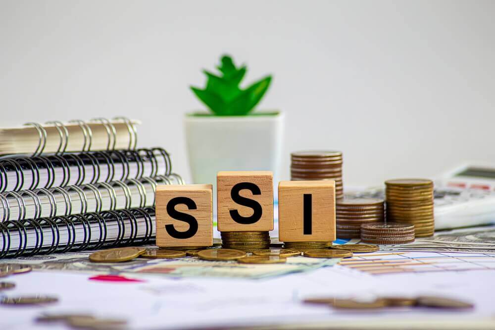 SSI income limits in 2026 concept with wooden SSI blocks, coins, and financial documents representing what counts as income for Supplemental Security Income.