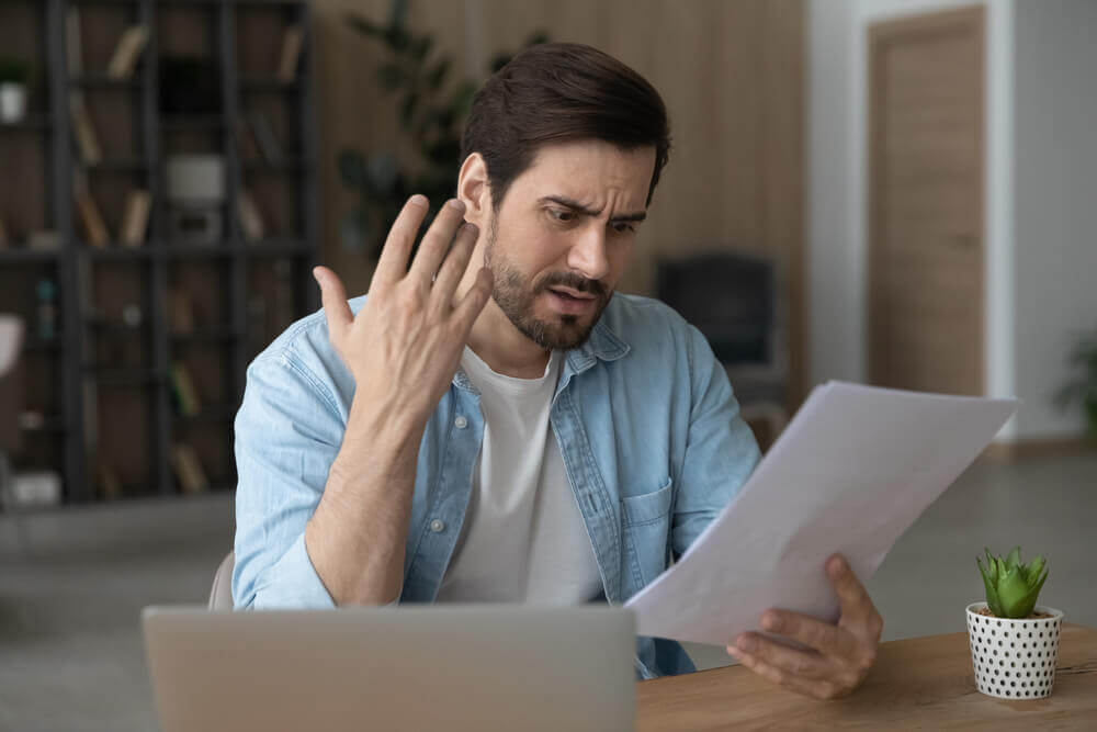 Man reviewing SSDI denial letter and paperwork feeling frustrated in 2026