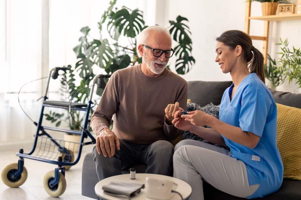 Nurse helping an older man check blood sugar levels, illustrating diabetes complications for SSD claims in Troy, MI.