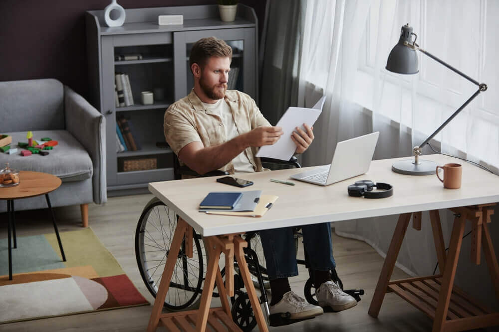 Man in wheelchair reviewing documents while working part-time during SSI application process